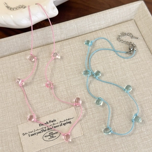 Close-up of pastel pink and blue beaded cord necklaces with transparent teardrop charms