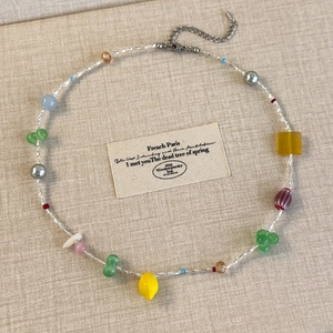 Détail macro du collier de perles colorées avec pendentif citron sur fond en lin
