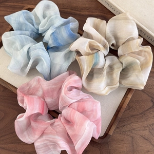 Gros chouchous en mousseline tie-dye avec texture marbrée posés sur un plateau