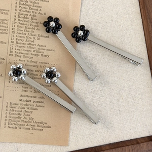 Detail von vier silbernen Metall-Haarspangen mit schwarz-silbernen Perlenblumen-Anhängern