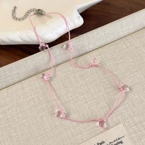 Detail of pink cord necklace featuring seven transparent water drop beads with silver clasp