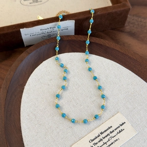 Bohemian beaded necklace with turquoise-blue faceted stones and gold chain in vintage style