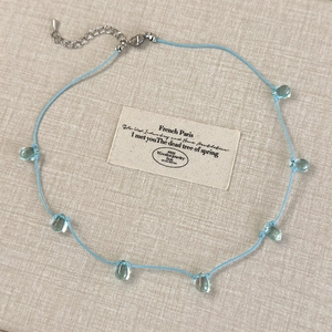 Detail of blue cord necklace with transparent teardrop pendants and adjustable silver clasp