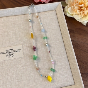 Détail d'un collier d'été aux perles colorées avec tubes jaunes et perles nacrées