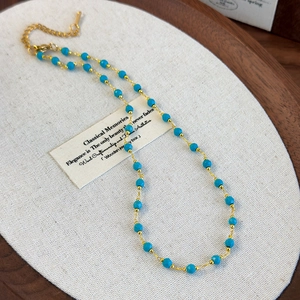Close-up of bohemian beaded necklace featuring blue faceted stones and lobster clasp