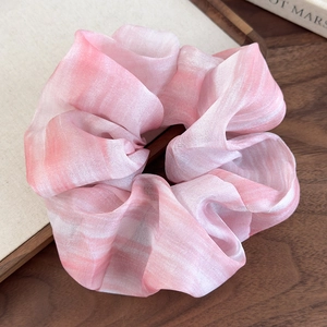 Détail de chouchou en mousseline tie-dye rose montrant le tissu en organza plissé léger