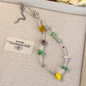 Vue détaillée du collier de perles multicolores avec chaîne d'extension argentée sur lin