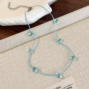 Detail of light blue cord necklace with transparent green waterdrop beads and silver clasp
