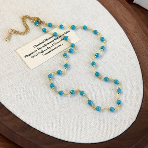 Close-up of golden beaded necklace with blue faceted stones and adjustable lobster clasp