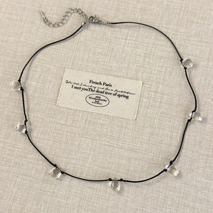Detail view of minimalist necklace with transparent water drop charms on black cord