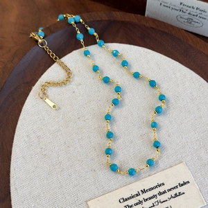 Bohemian light blue stone necklace with gold chain and lobster clasp on linen