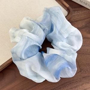 Gros plan du chouchou en mousseline tie-dye bleu et blanc avec texture nacrée douce