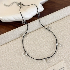 Detail of a transparent water drop beaded necklace with black cord and metal lobster clasp