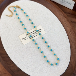 Detail of bohemian gold chain necklace with sky blue faceted beads and lobster clasp