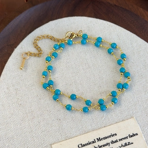 Close-up of bohemian double-layer beaded bracelet with blue stones and gold chain