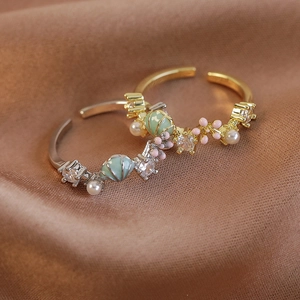 Adjustable floral shell rings with pearls and zircon on elegant brown satin background