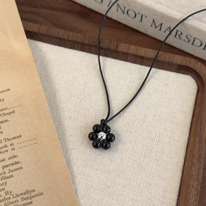 Detailansicht einer schwarzen Perlenkette mit Blume auf Vintage-Hintergrund im Holztablett