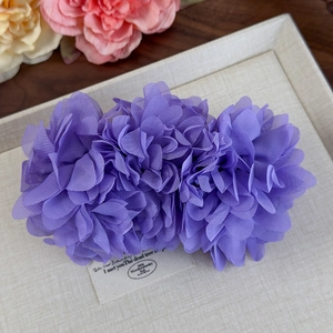 Gros plan d'une pince à cheveux à fleurs violettes aux textures de pétales superposés
