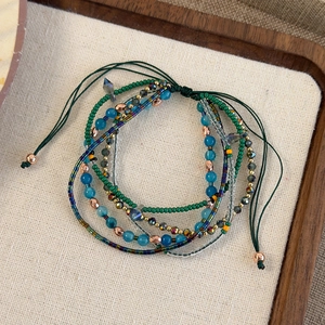 Macro view of multi-layered bohemian beaded bracelet with adjustable woven green cord