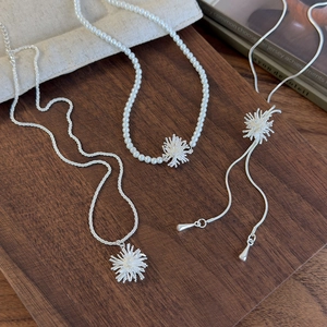 Silver firework adjustable pearl and titanium steel necklace set on a dark wood background