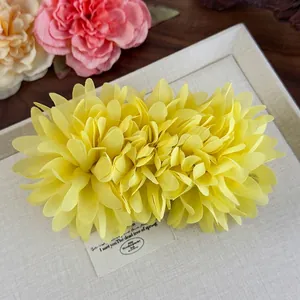 Gros plan d'une grande pince à cheveux fleur en tissu jaune sur un plateau en lin