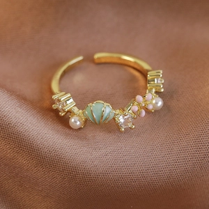 Detailansicht goldener offener Ring mit grüner Muschel, rosa Emailleblume und Perlen