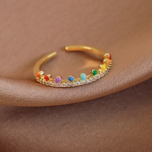 Détail de la bague arc-en-ciel émaillée or avec zircons sur satin champagne