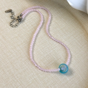 Detail of pink crystal beads and light blue donut pendant on a necklace