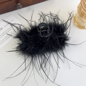 Vue détaillée de la pince à cheveux en plumes noires sur un bureau élégant et moderne