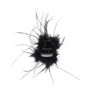 Détail d'une pince à cheveux en plumes noires avec plastique brillant et ressort en métal