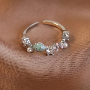 Detailansicht Emaille-Muschelring mit rosa Blumen, Perlen und Zirkonia auf brauner Seide
