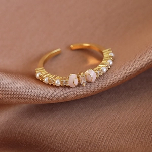 Nahaufnahme eines verstellbaren Goldrings mit einer rosa Emaille-Schleife und Perle