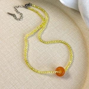 Detail of yellow faceted acrylic beads with an orange agate-style donut pendant and clasp