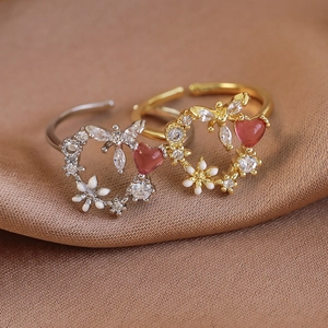 Detail of adjustable flower rings with pink heart stones and zircons on satin