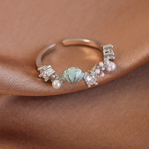 Detailaufnahme des Muschelblütenrings mit Perlen und Zirkonia auf braunem Satin