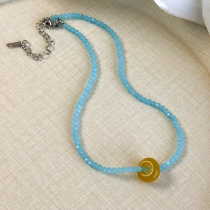 Detail of light blue crystal beads and a yellow round agate pendant on a necklace