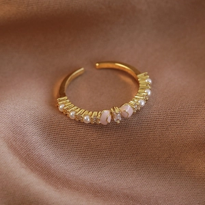 Detailaufnahme der goldenen Schleifenring mit Zirkonia und Perlen auf Seidenstoff