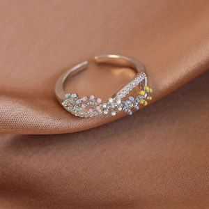 Close-up of silver ring with colorful enamel flowers and pave-set zircons on silk fabric