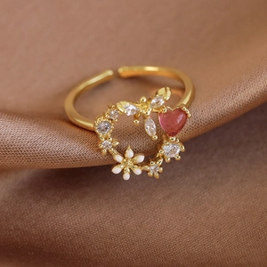 Detailed close-up of a floral ring with pink heart stone and white enamel on satin