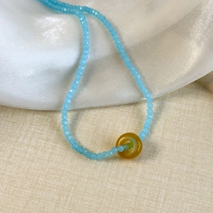 Macro detail of faceted light blue beads with a bright yellow circular pendant