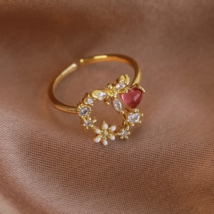 Macro shot of gold adjustable ring featuring pink heart gem and white enamel flowers