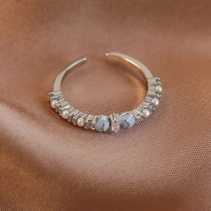 Detailaufnahme des silbernen Schleifenrings mit Perlen und blauen Herz-Zirkonia