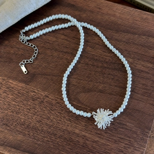 Close-up of adjustable silver firework pendant necklace with white pearls on wood background