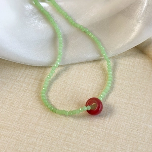 Close-up of fresh light green crystal beaded necklace with a red circle pendant detail