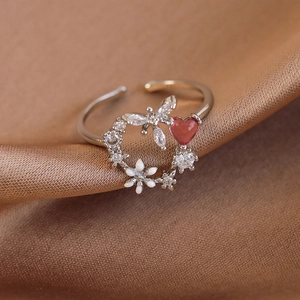 Macro shot of white enamel flowers and pink heart zircon on silver floral open ring