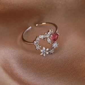 Macro shot of rose gold floral ring with pink heart stone and white enamel flowers