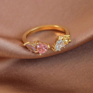 Détail macro d'une bague dorée ajustable avec cœur rose et pierres de zircon colorées
