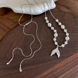 Elegant fishtail pearl necklace with adjustable silver chain on a walnut tray