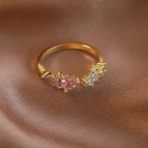 Vue macro d'une bague coeur dorée avec oxydes de zirconium roses sur soie brune