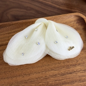 Détail d'une pince à cheveux papillon en tulle avec strass et lettrage Love doré élégant